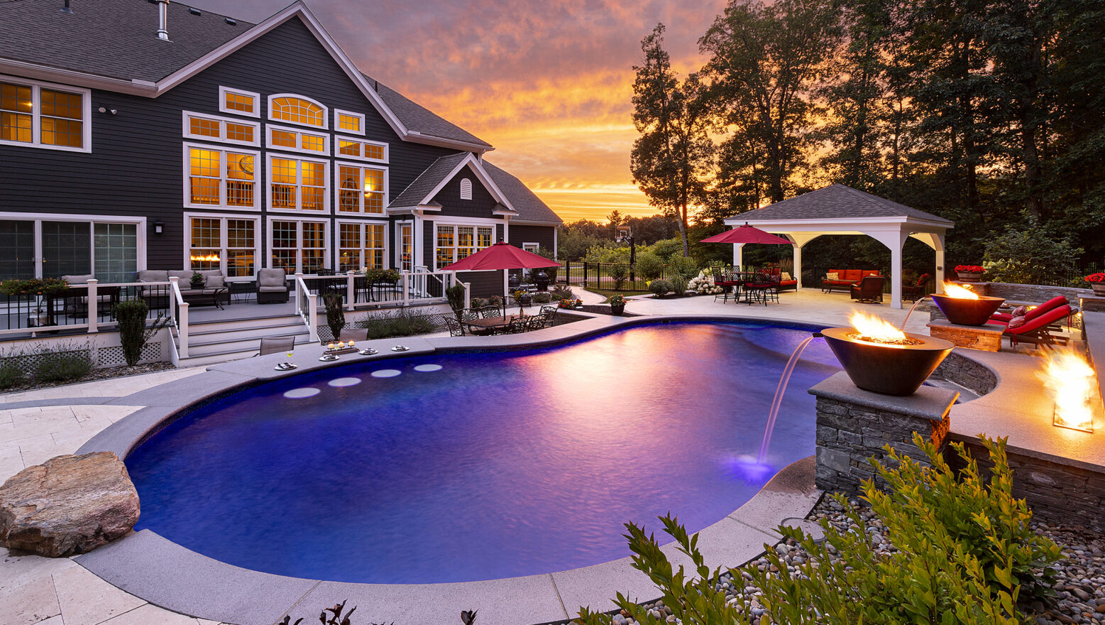 Dex by Terra Pool deck, water/fire features, and jump rock, looking toward the back of the home in Sterling, Massachusetts