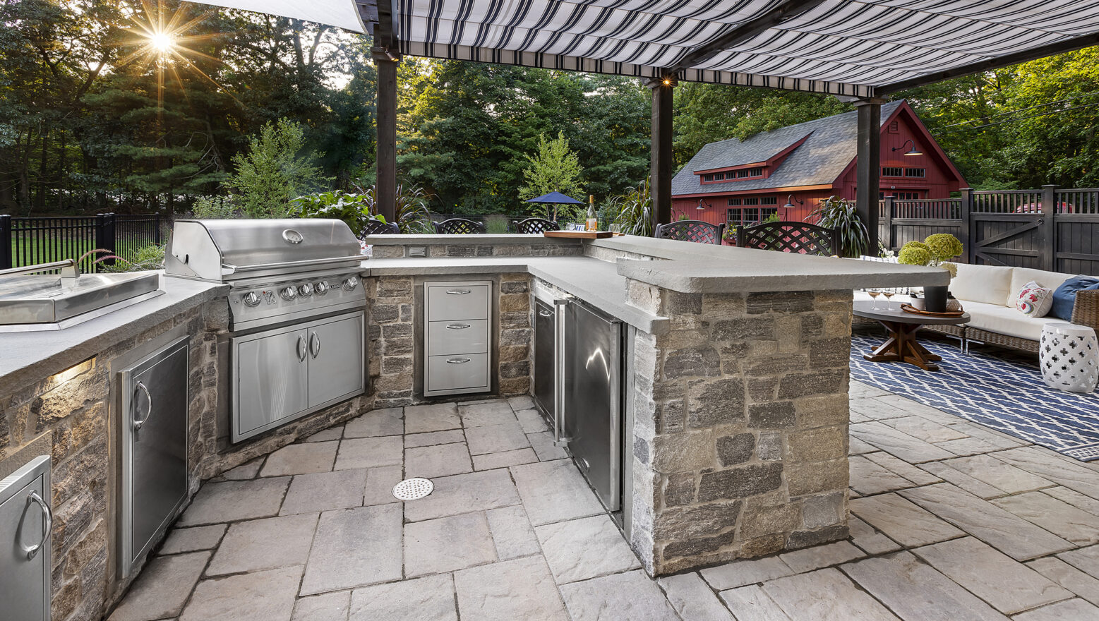 Outdoor Kitchen with grill, and stainless steel appliances under pergola. Dex by Terra residential hardscape in Stow, MA.