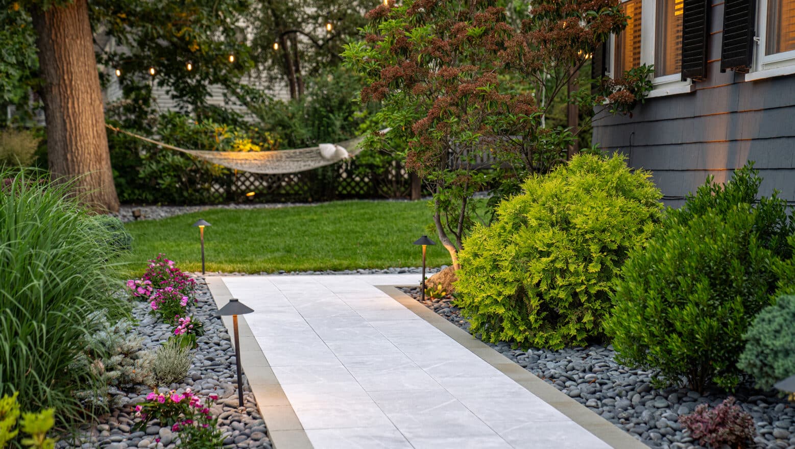 A stone paver walkway leads to a backyard hammock in Needham, MA.