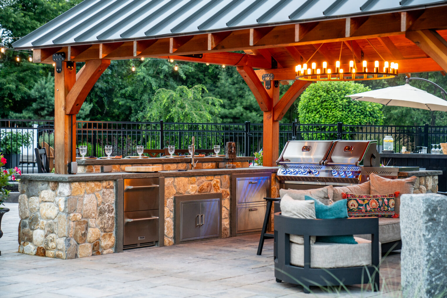 The outdoor kitchen under the client built pergola was furnished with professional grade appliances. New England Rounds stone veneer was used to build the kitchen.