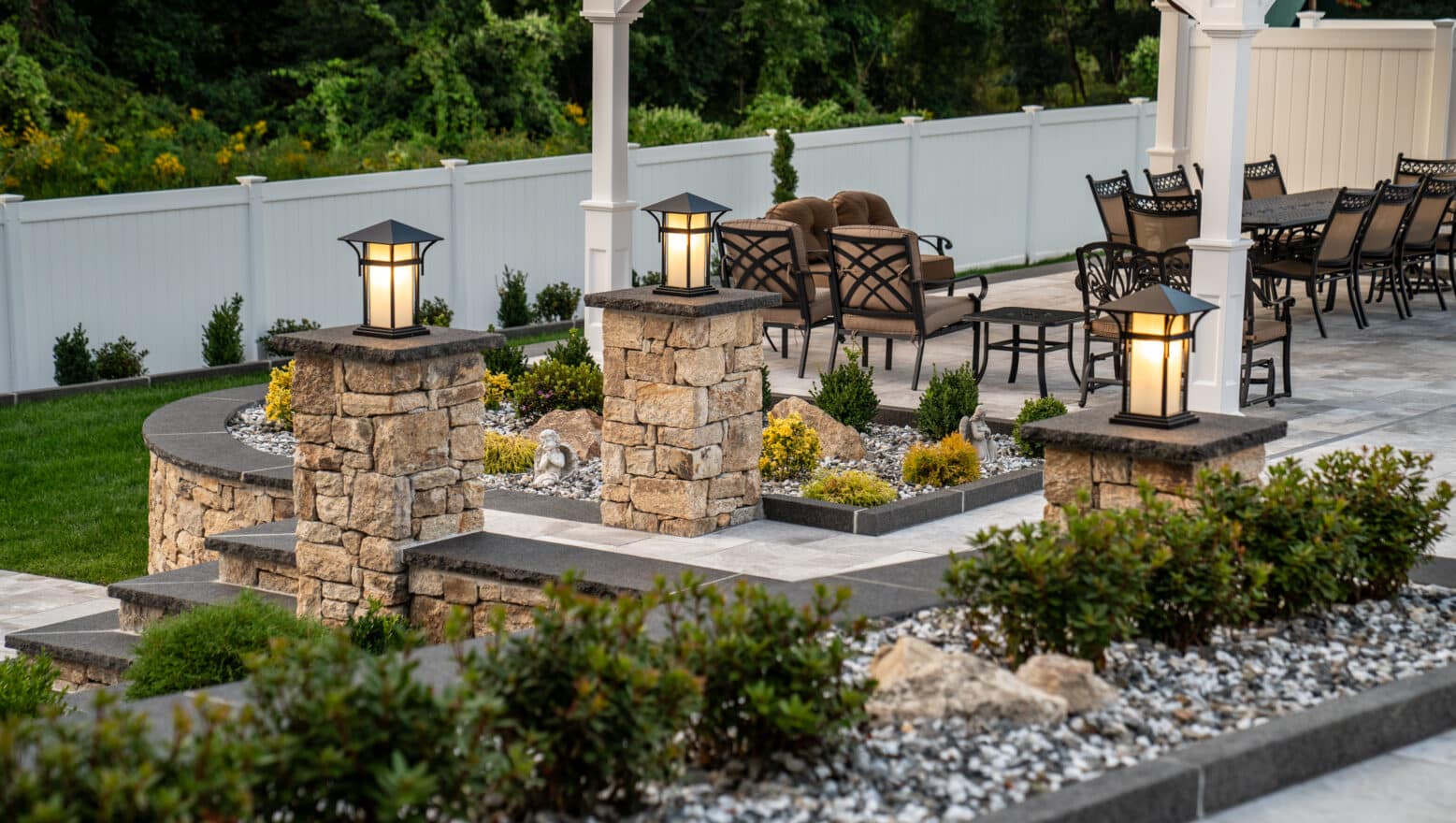 Stone columns and landscaping elevate this high-end backyard built by Dex by Terra in Grafton, Massachusetts.