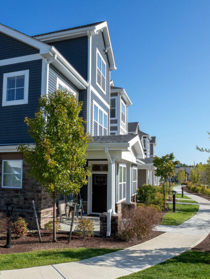 Landscaping with concrete walkways & stone veneer at luxury apartments in MA. Landscape & hardscape work by Dex by Terra.