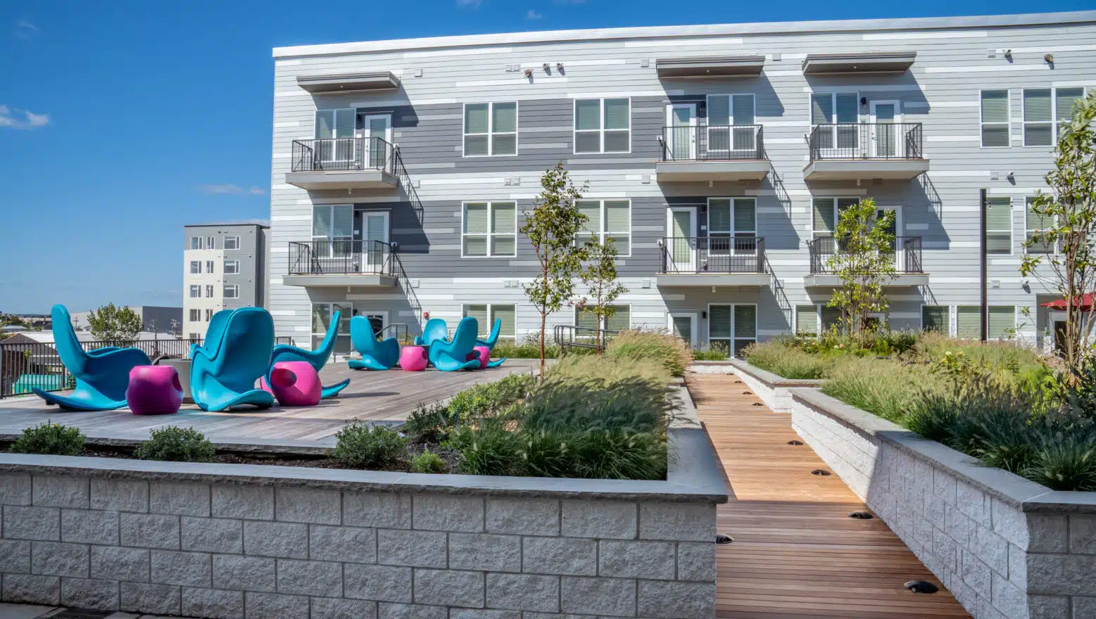 Stone retaining walls & ramp to an elevated lounge deck at V2 Apartments in Chelsea, MA. Dex by Terra Commercial hardscape.